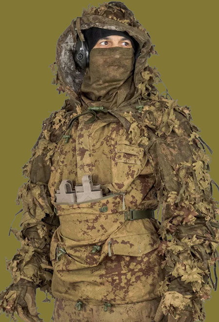 Person wearing a full Kicking Mustang camouflage military outfit with helmet and mask on a green background