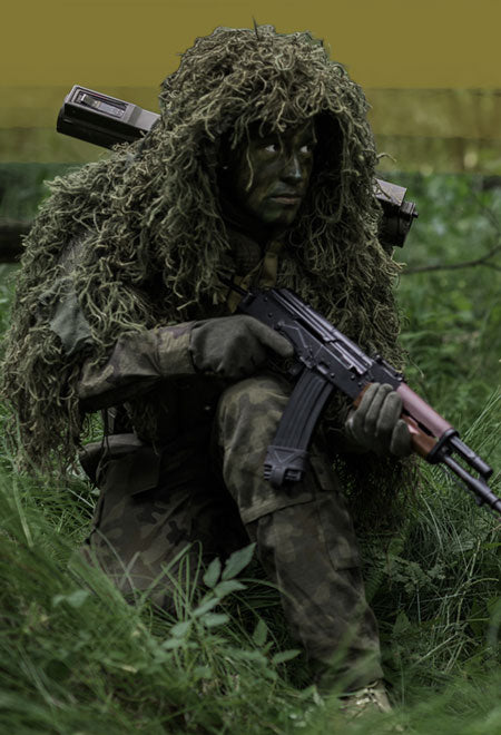 airsoft player in camouflage gear with airsoft rifle in a forest setting
